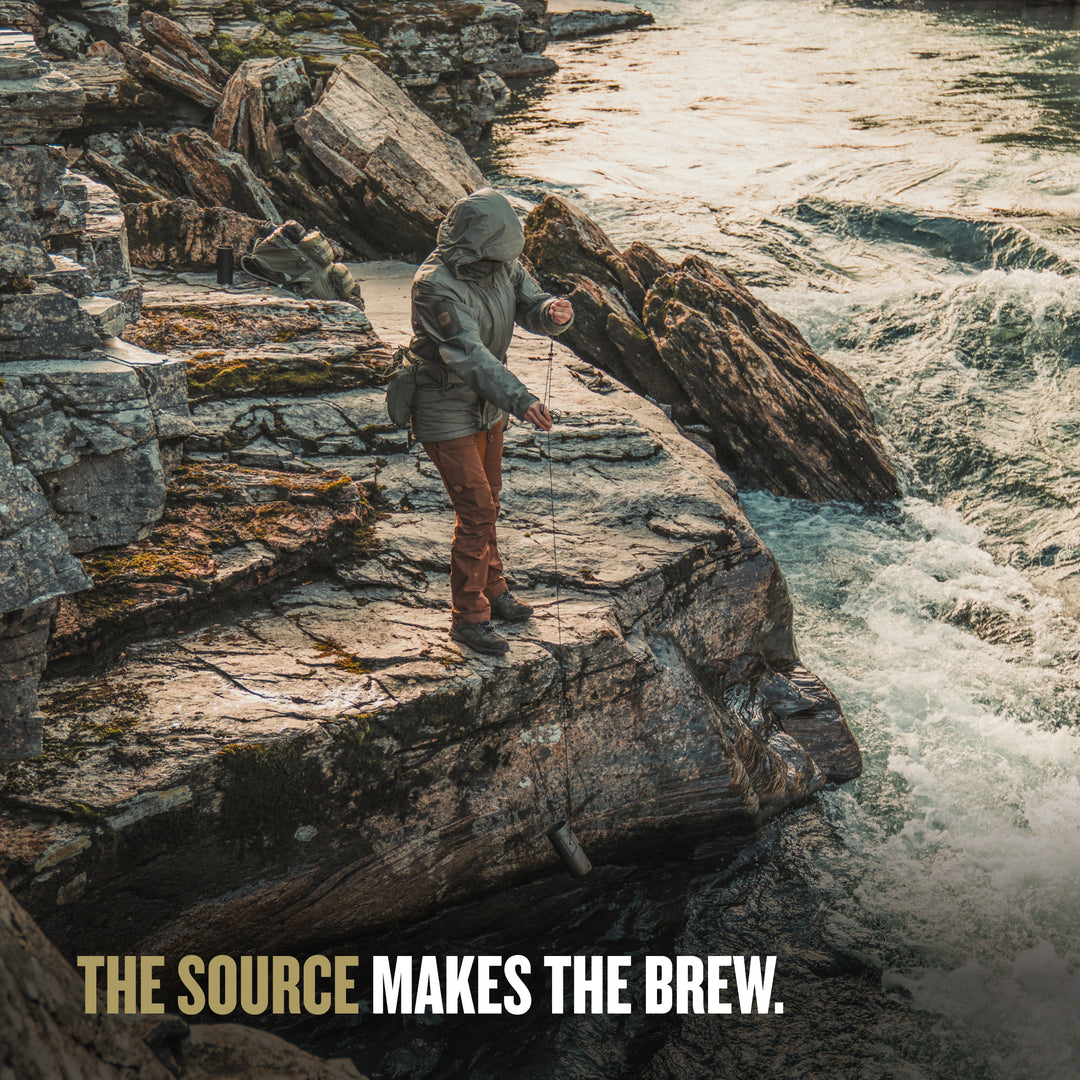 Person fishing on a rocky outcrop by a flowing river. / PLUS COOK LID (V2) / Natural / Black