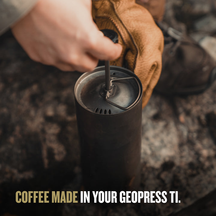 Person using a GeoPress Ti coffee maker outdoors. / PLUS COOK LID (V2) / Natural / Black